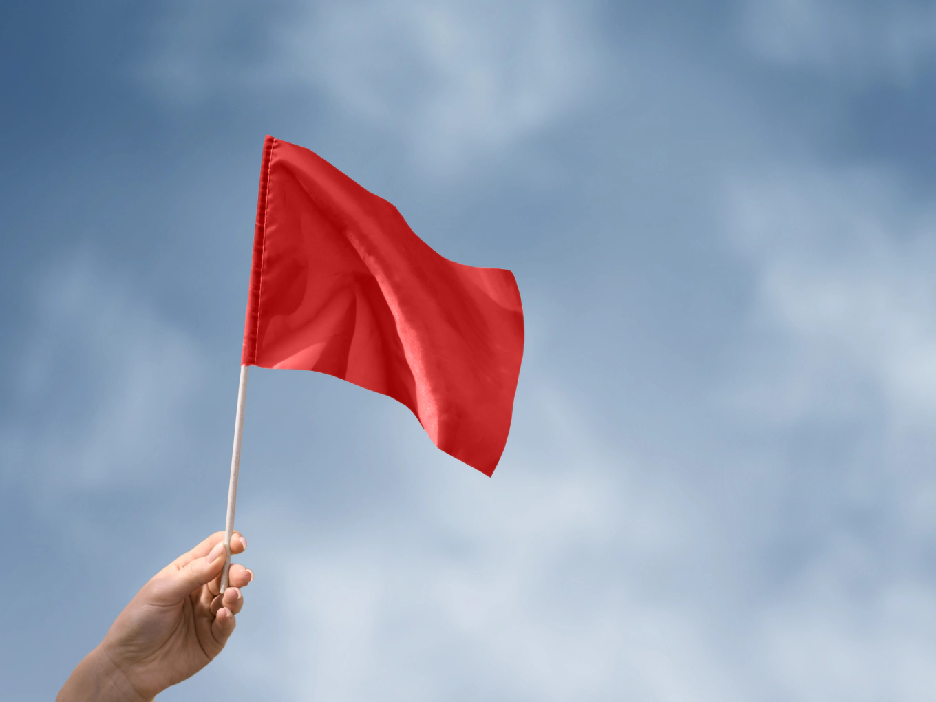Una mano sventola una bandiera rossa contro il cielo