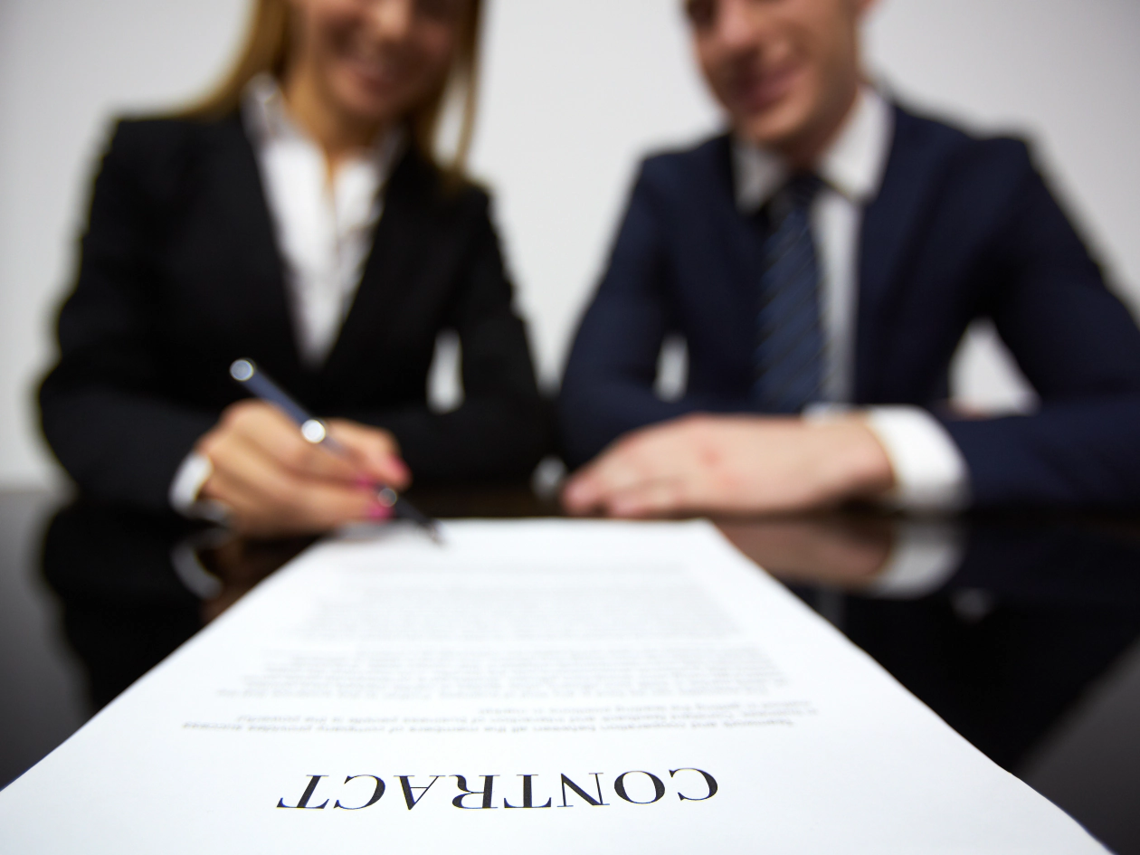 Due professionisti firmano un contratto al tavolo di un incontro